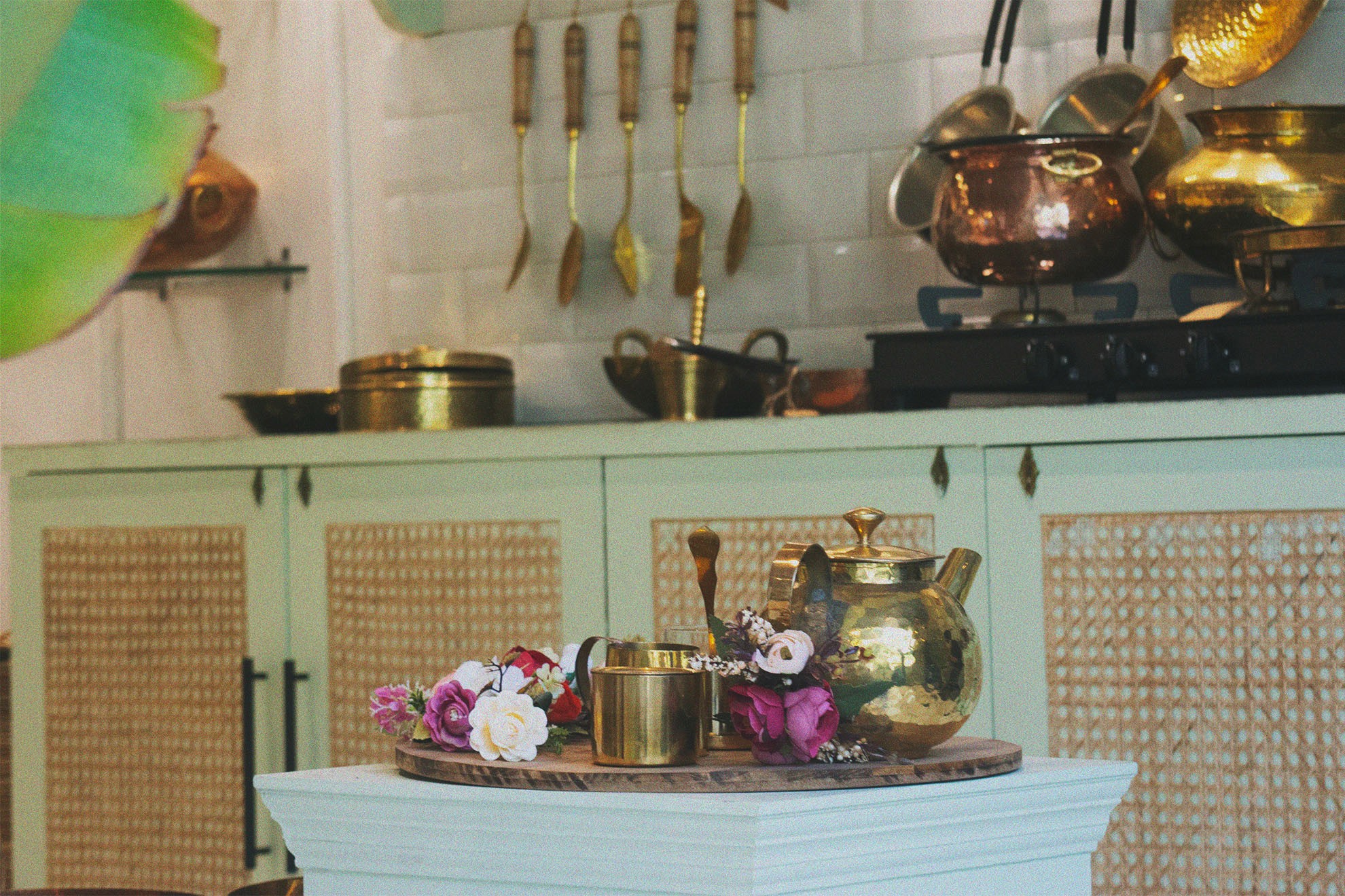 Brass and copper cookware, a kettle and flowers on a counter in the P-Tal store