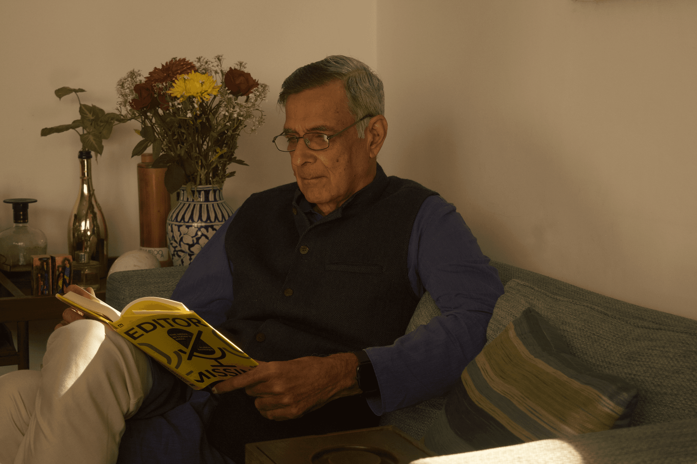 Mohit Satyanand reading a yellow book on a sofa, still from the launch film for ThisDay's podcast The Reader's Room