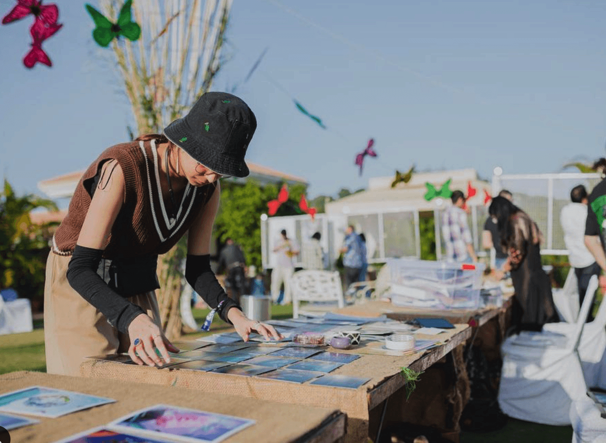 Riya Kumari arranging her art prints on a table at an outdoor pop-up market