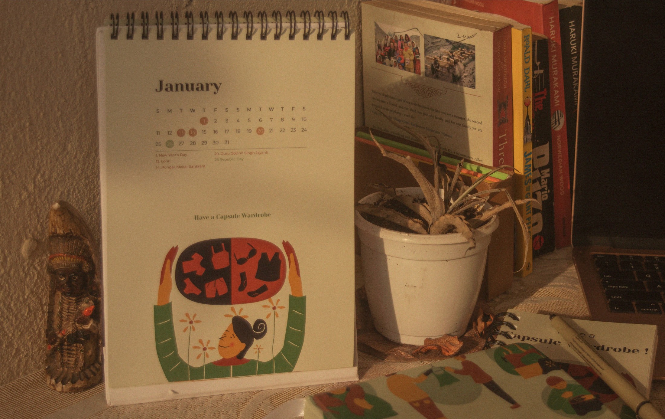 Photo of the 2021 calendar on a desk with a plant and art supplies